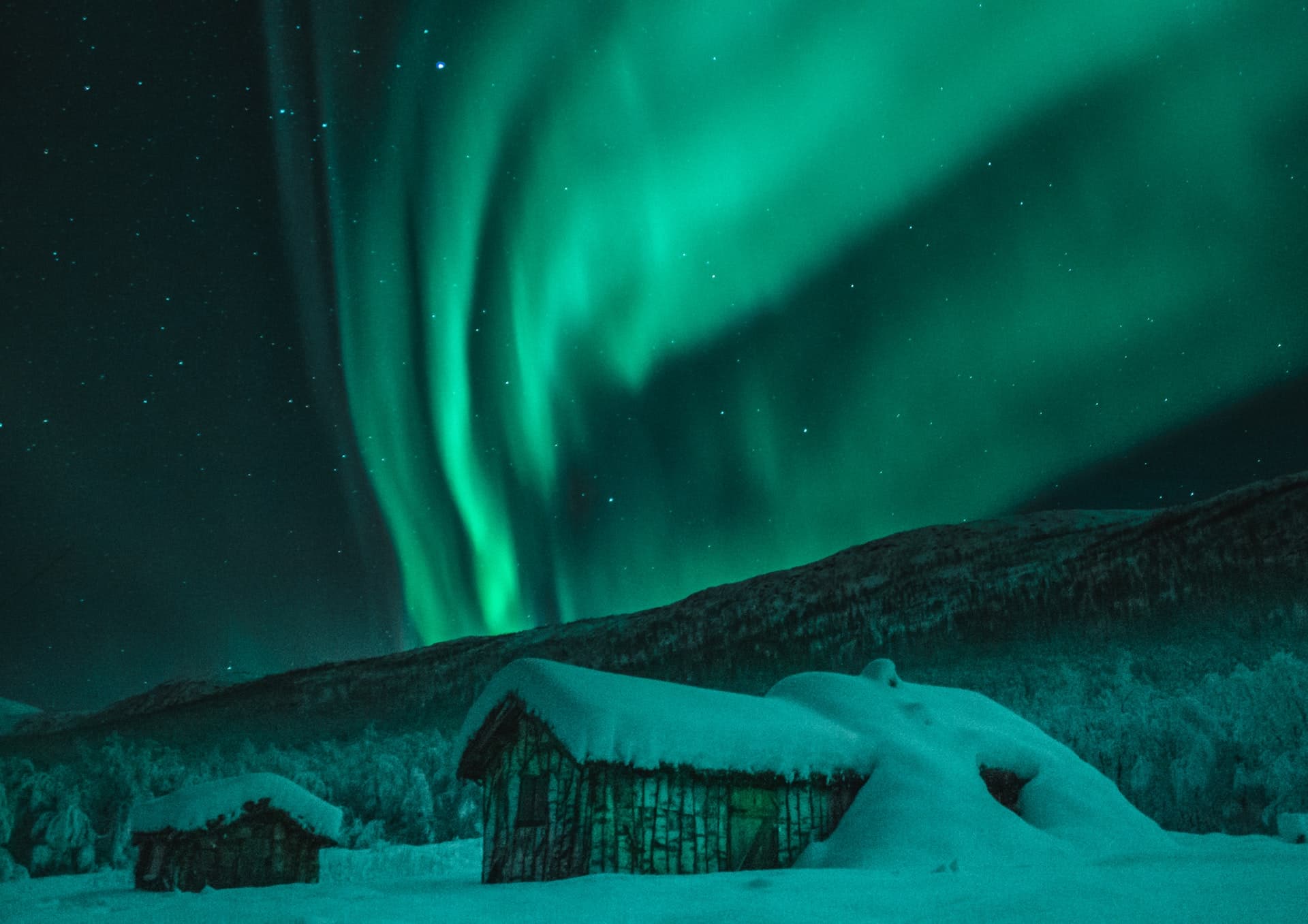 Snow-covered cabins under the northern lights in the Alta valley