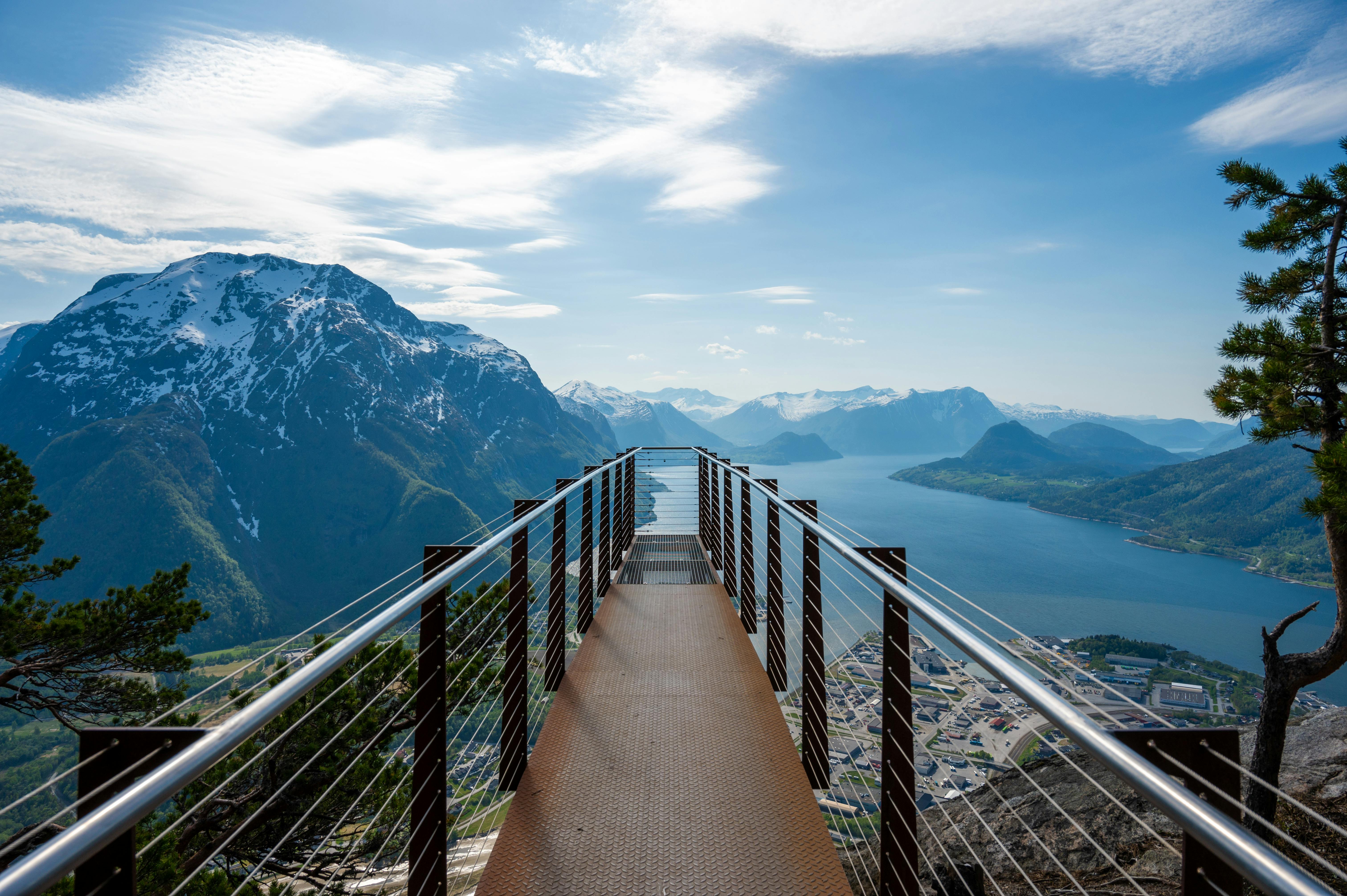 Ornesvingen viewing platform extending over the fjord with snow-capped mountains and Geirangerfjord below