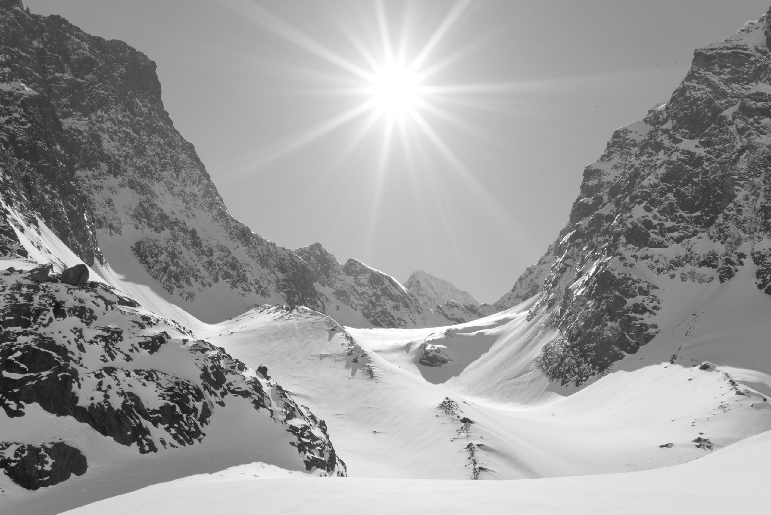 Ski tourer making switchbacks up a snow slope in the Lyngen Alps with the fjord visible below