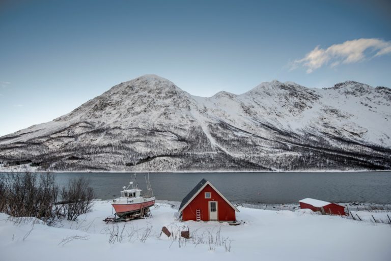 Snow-covered islands in Lyngenfjord with mountains rising from the frozen shoreline