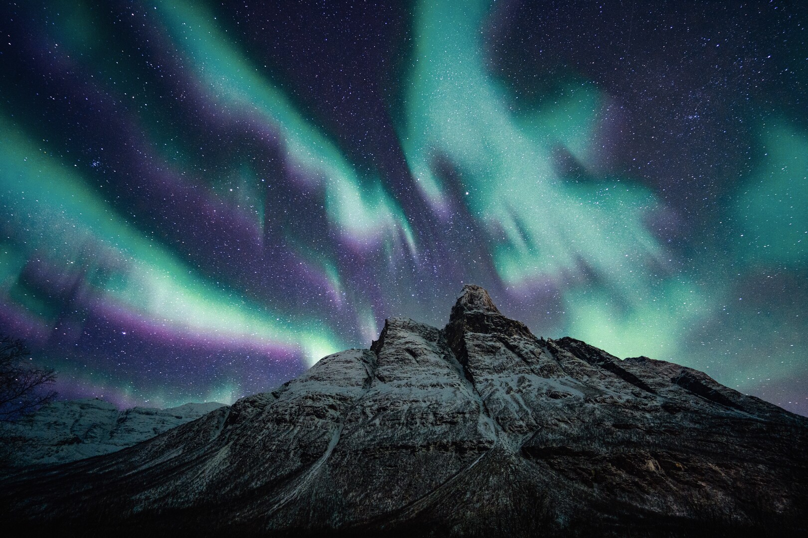 Green and violet aurora over the snow-covered peak of Otertind in Signaldalen, Storfjord