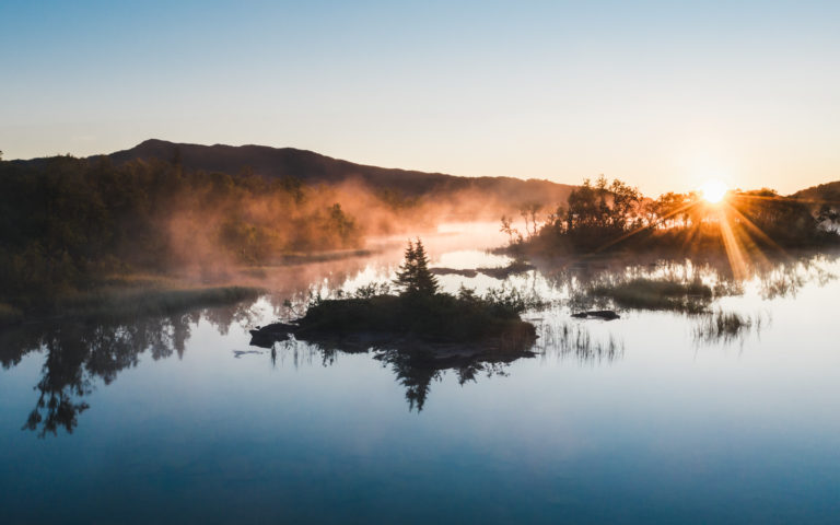A lake on Senja under the amber light of the midnight sun