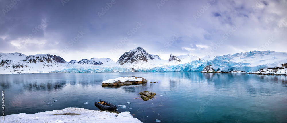Arctic Kvaløya landscape with snow on mountain peaks, birch forest in the valley and a calm fjord